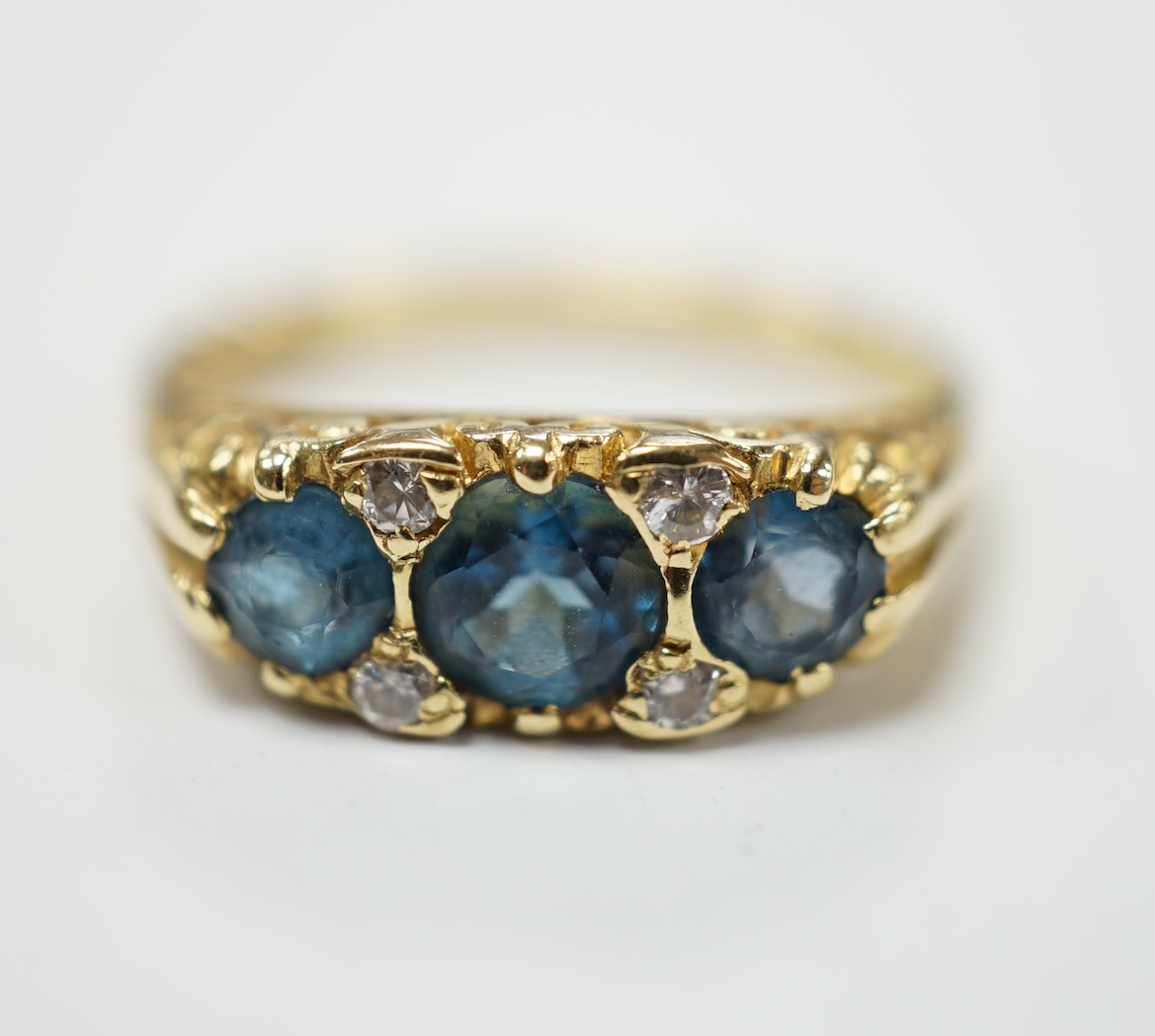 A modern Edwardian style 18ct gold and three stone blue topaz set ring, with diamond chip spacers, size M, gross weight 4.1 grams. Fair condition.